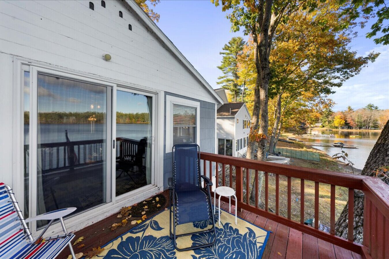 A deck with a blue outdoor chair, a small table, and a glass door leading to a covered patio.