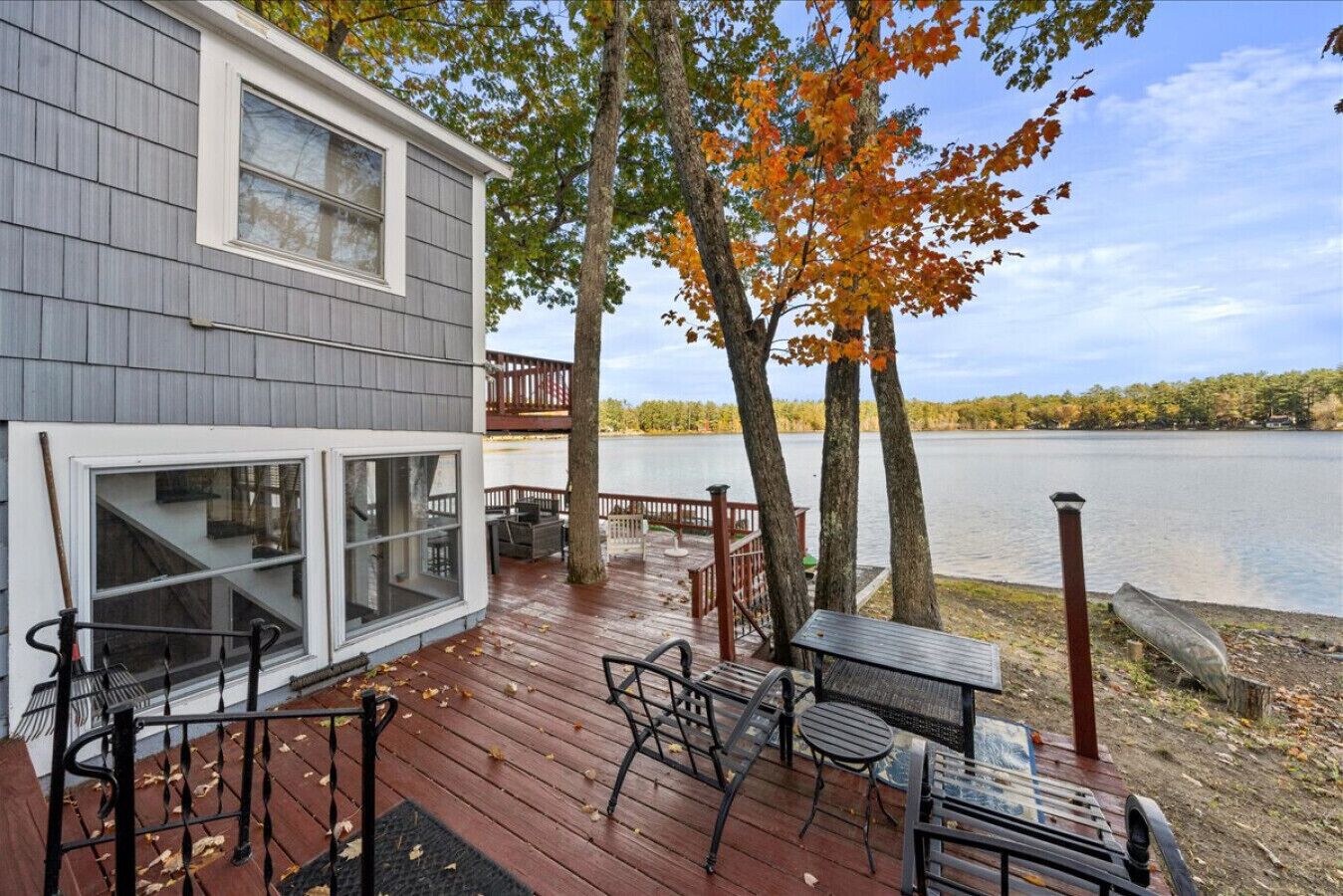 Um deck com móveis de exterior com vista para um lago, deck de madeira e vista para a água.