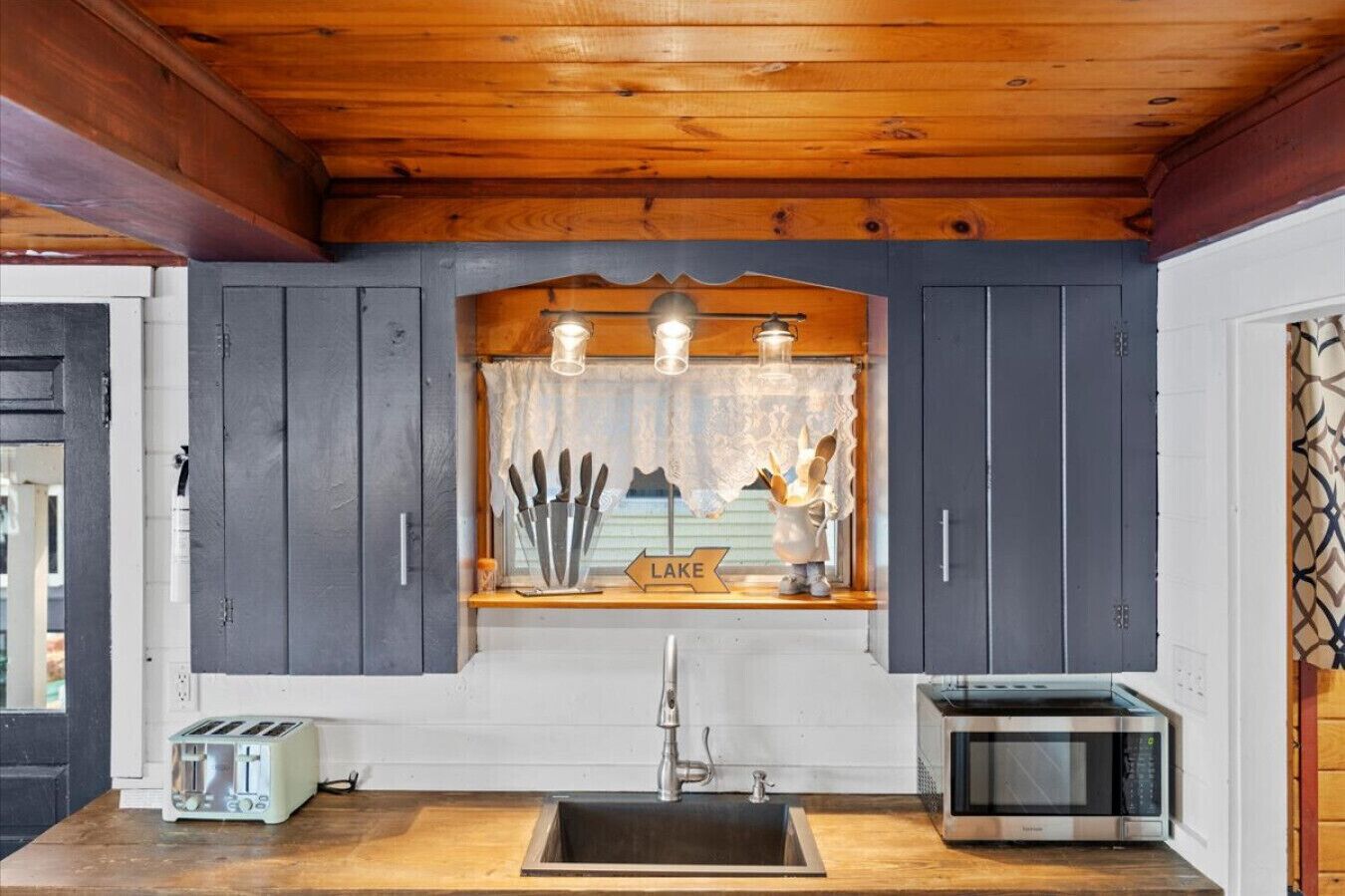 Une cuisine avec un plafond en bois, un évier, un grille-pain et un four à micro-ondes.