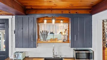 Une cuisine avec un plafond en bois, un évier, un grille-pain et un four à micro-ondes.