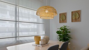 A dining area with a table, chairs, a hanging light fixture, a potted plant, and framed artwork on the wall. - Sunstay Cosy Flat I Cristo Malaga (Málaga)