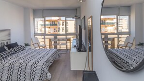 Une chambre moderne comprenant un lit, un bureau, une chaise, un téléviseur et un grand miroir.