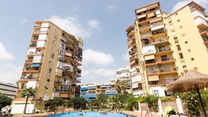 Un immeuble résidentiel de grande hauteur doté de nombreux balcons, d’une piscine et entouré de verdure.