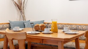 A breakfast setting with a wooden table, chairs, and a basket of bread. - Cosy apartment in the center with a garden (Kirchberg in Tirol)