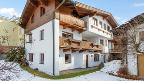 A multi-story chalet with wooden balconies and a white facade. - Cosy apartment in the center with a garden (Kirchberg in Tirol)