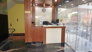 Uma área de recepção com uma mesa de madeira, um relógio na parede e um aviso de 'Não Fumar'.