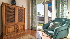 Une pièce avec un meuble en bois, un fauteuil turquoise et un tapis à motifs.