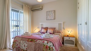 Une chambre à coucher avec une couvre-lit à motifs floraux, une tête de lit blanche et une table de chevet avec une lampe.