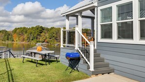 Ein Haus mit Veranda, Grill und einem Tisch mit Kürbisdeko.
