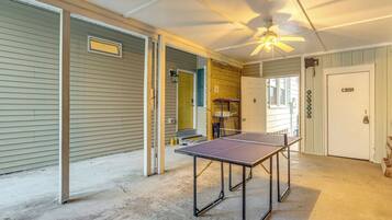 A room with a ping pong table, a ceiling fan, and a door with a 'Welcome' sign.