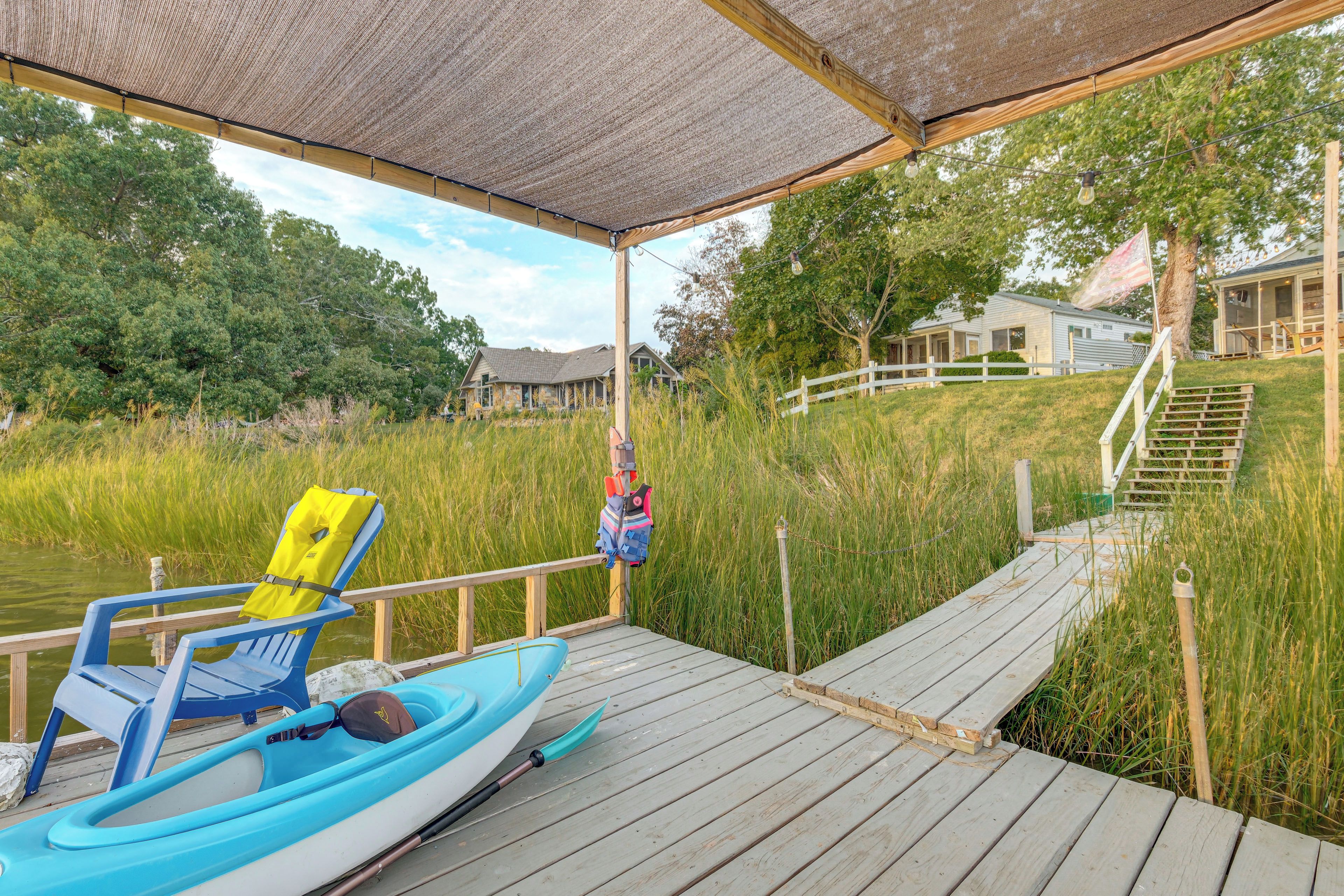 A wooden dock leading to a house with a covered area.