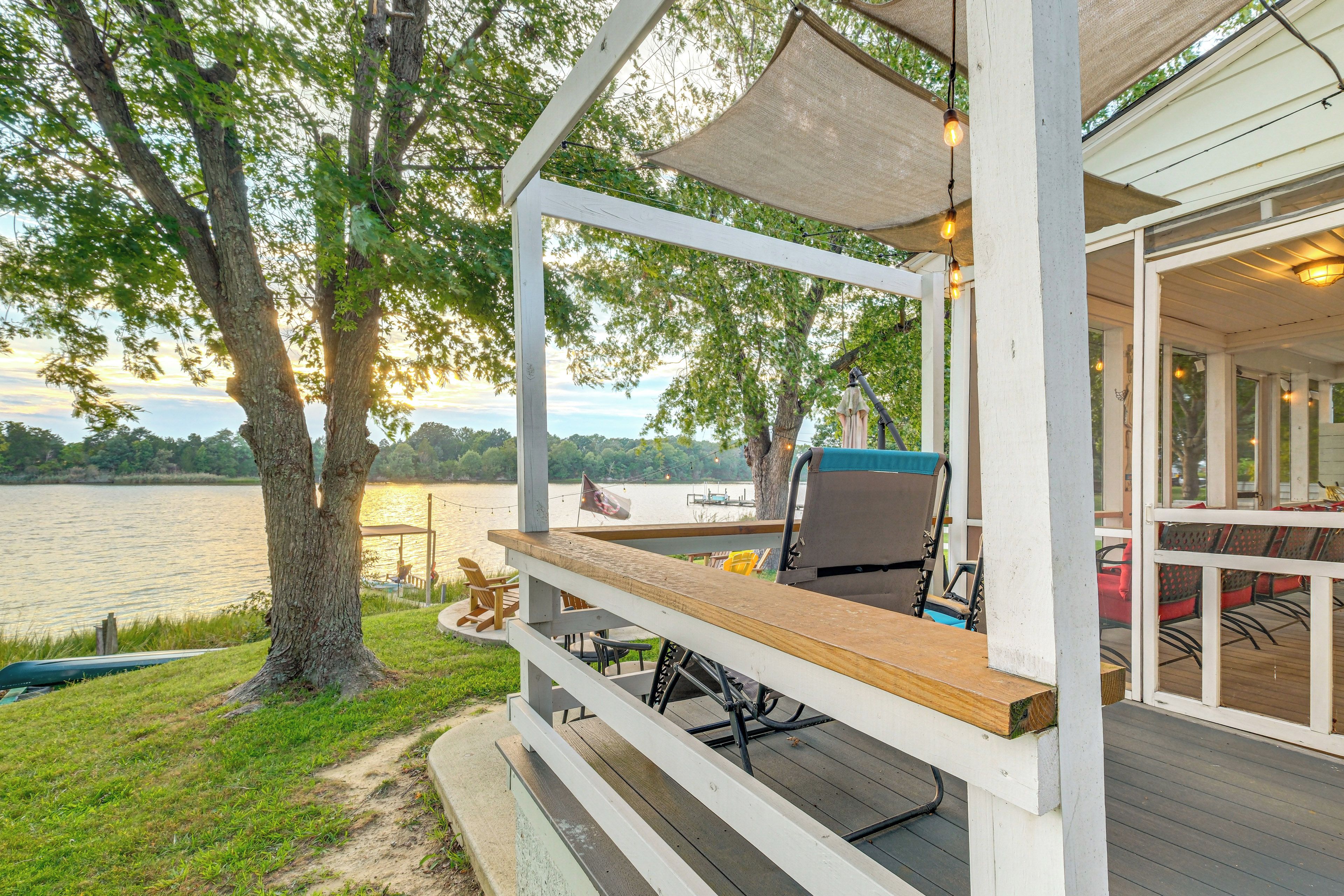 A covered deck with outdoor seating, overlooking a lake.