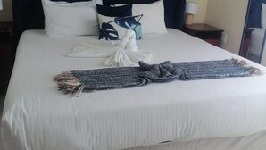 Un letto ben rifatto con lenzuola bianche, una testiera scura e una coperta a quadri blu e bianchi.