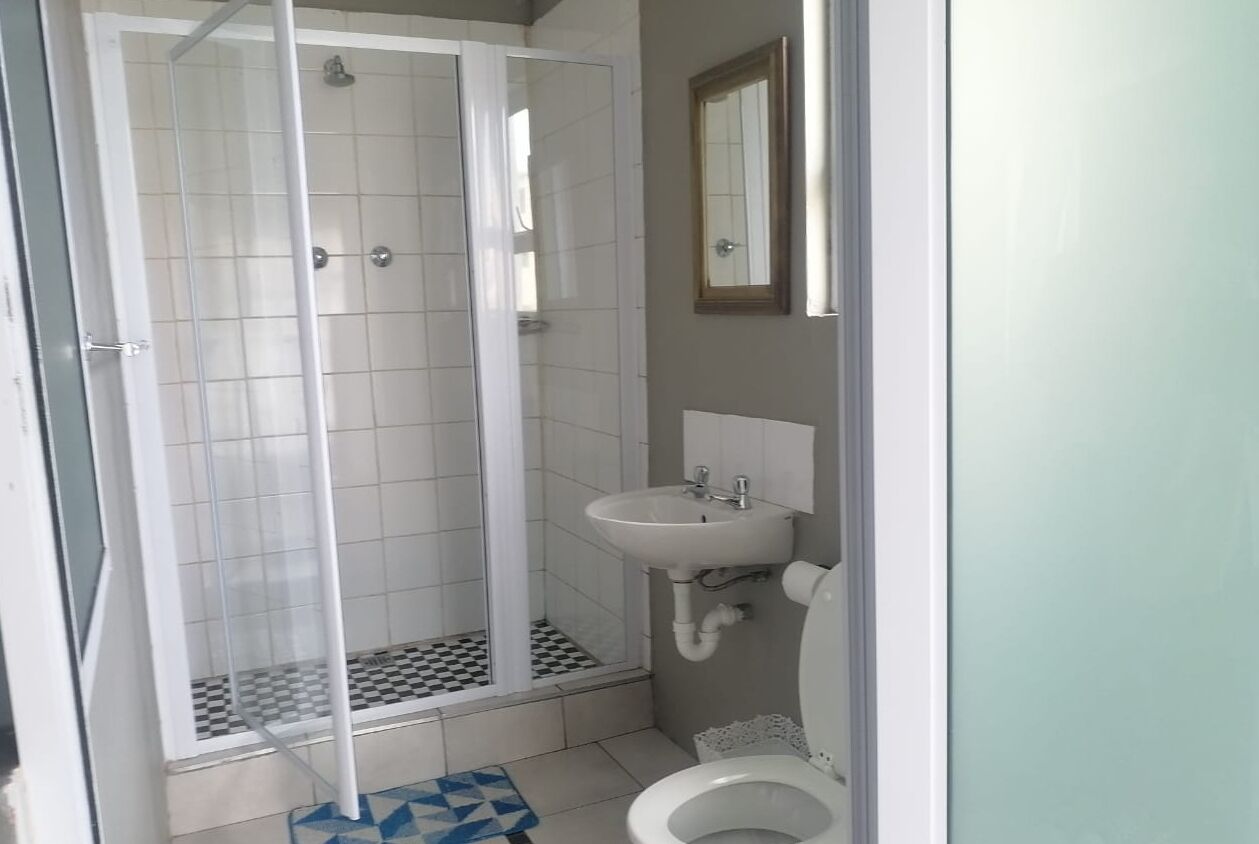 A bathroom with a shower enclosure, a sink, and a toilet.