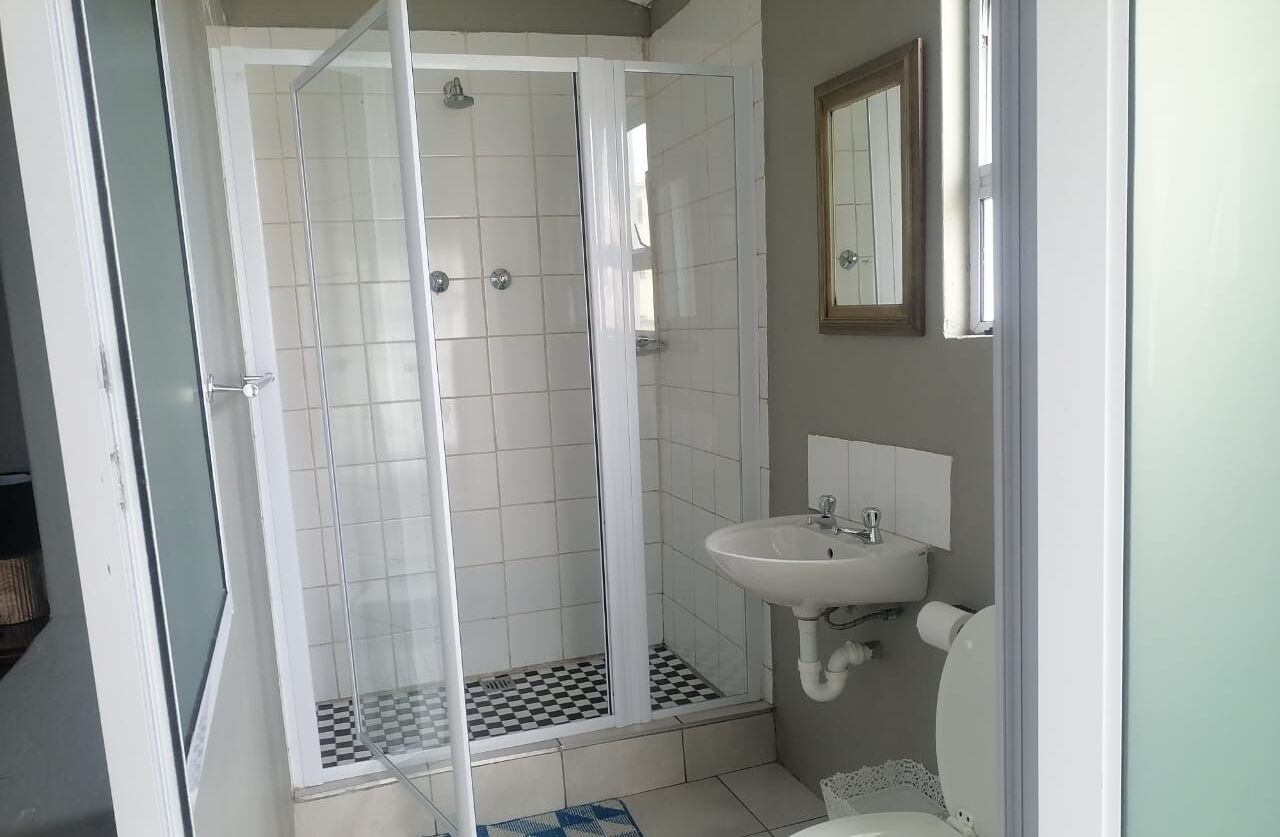A bathroom with a glass-enclosed shower, a sink, and a toilet.