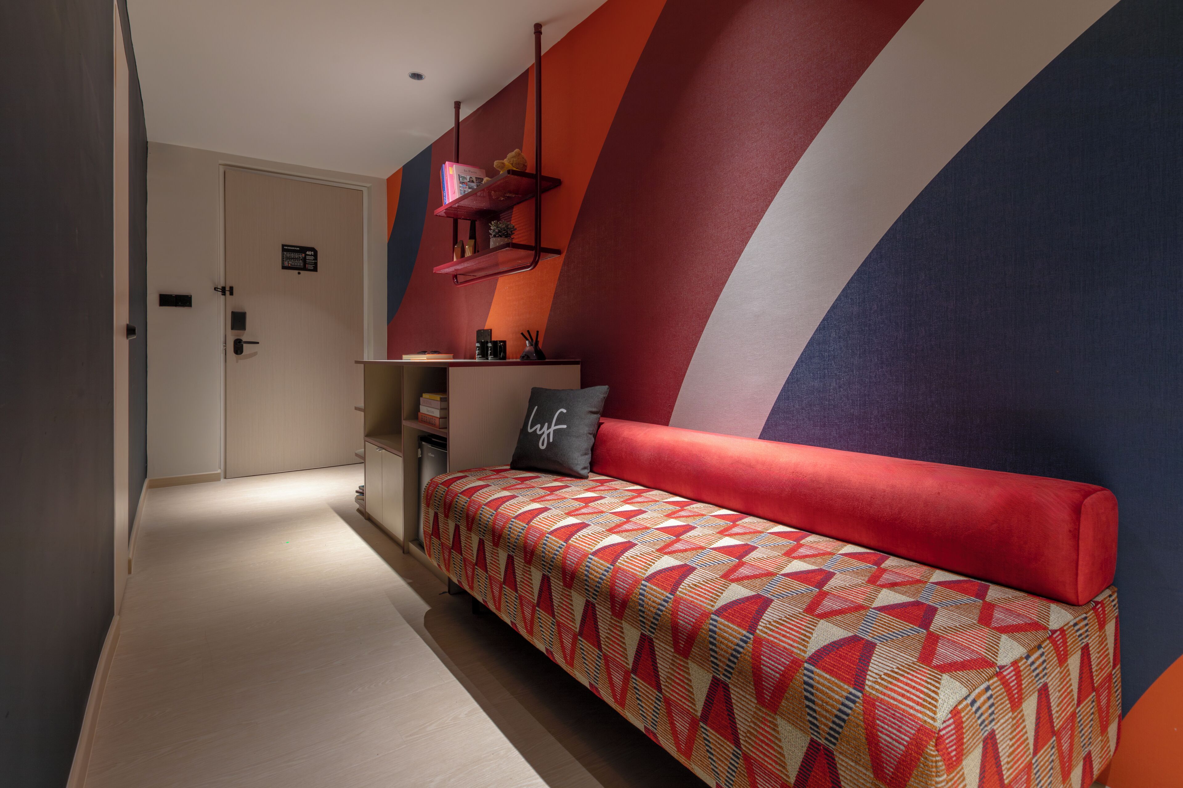 Un intérieur moderne avec un canapé à motifs, une bibliothèque et un mur orné de motifs géométriques.