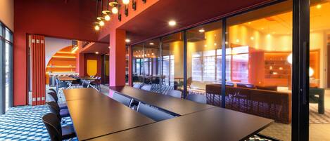 A modern conference room with a long table, multiple chairs, and a patterned carpet.