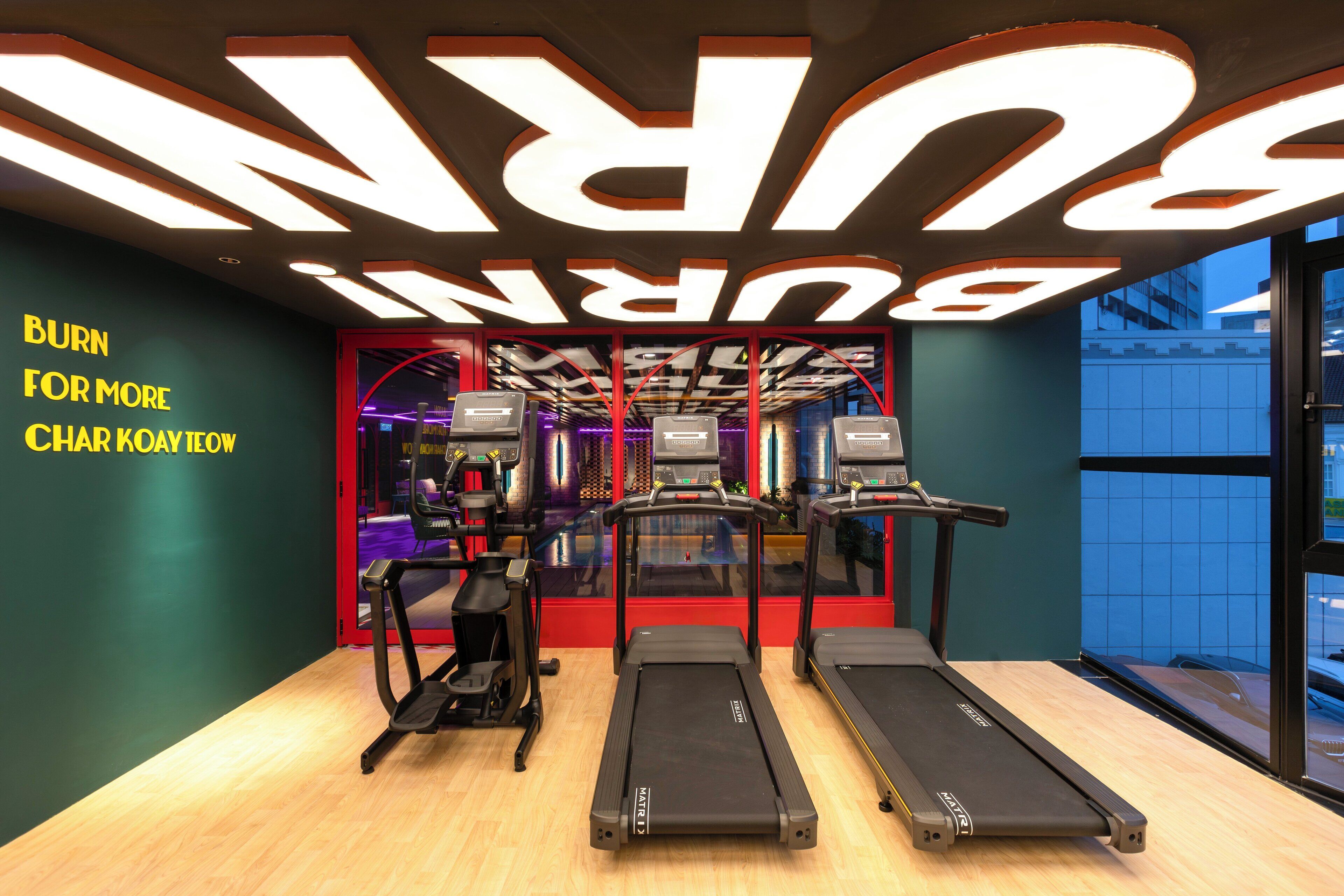 A gym with treadmills, a stationary bike, and a wall with motivational text.