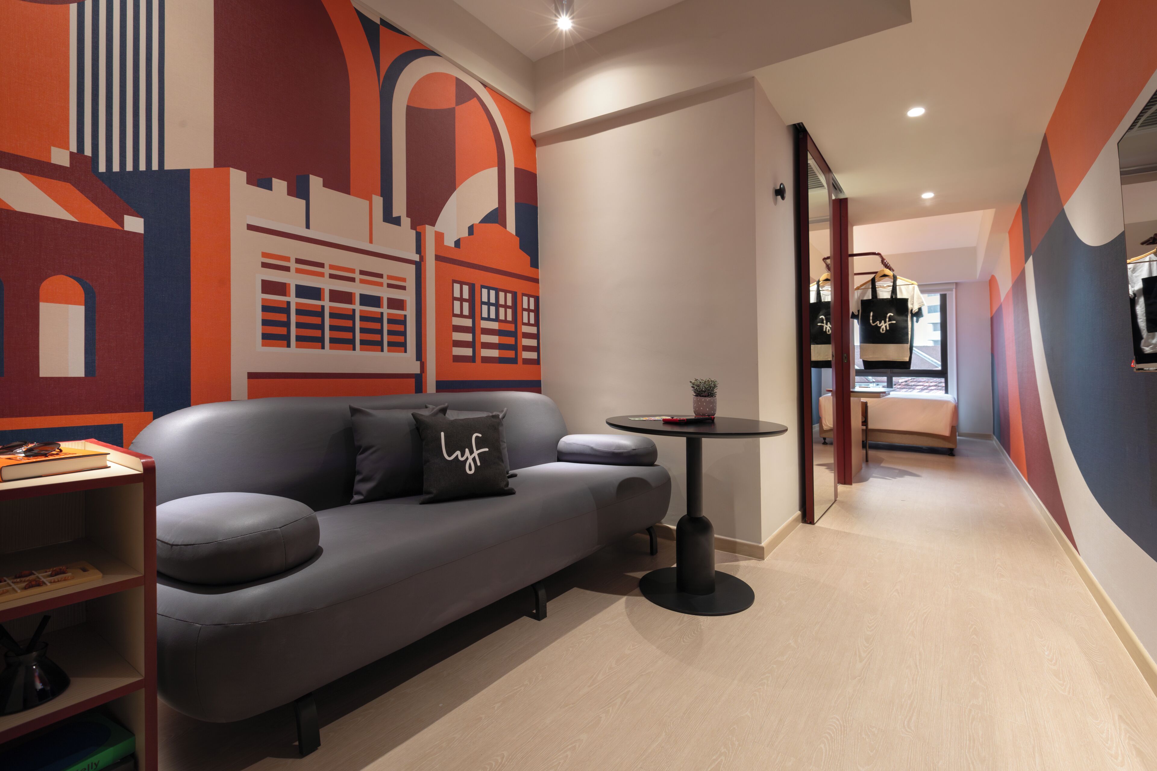 Ein modernes Interieur mit einem grauen Sofa, einem kleinen runden Tisch und einem Bücherregal.