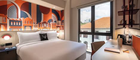 Une chambre d’hôtel moderne dotée d’un grand lit, d’un bureau avec une chaise, d’une grande fenêtre et d’une fresque représentant un paysage urbain sur le mur.