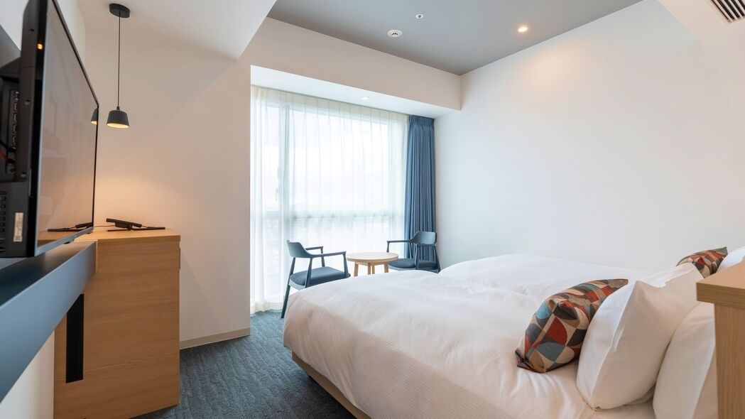 Een hotelkamer met een bed, een bureau, een stoel, een kleine tafel en een televisie.