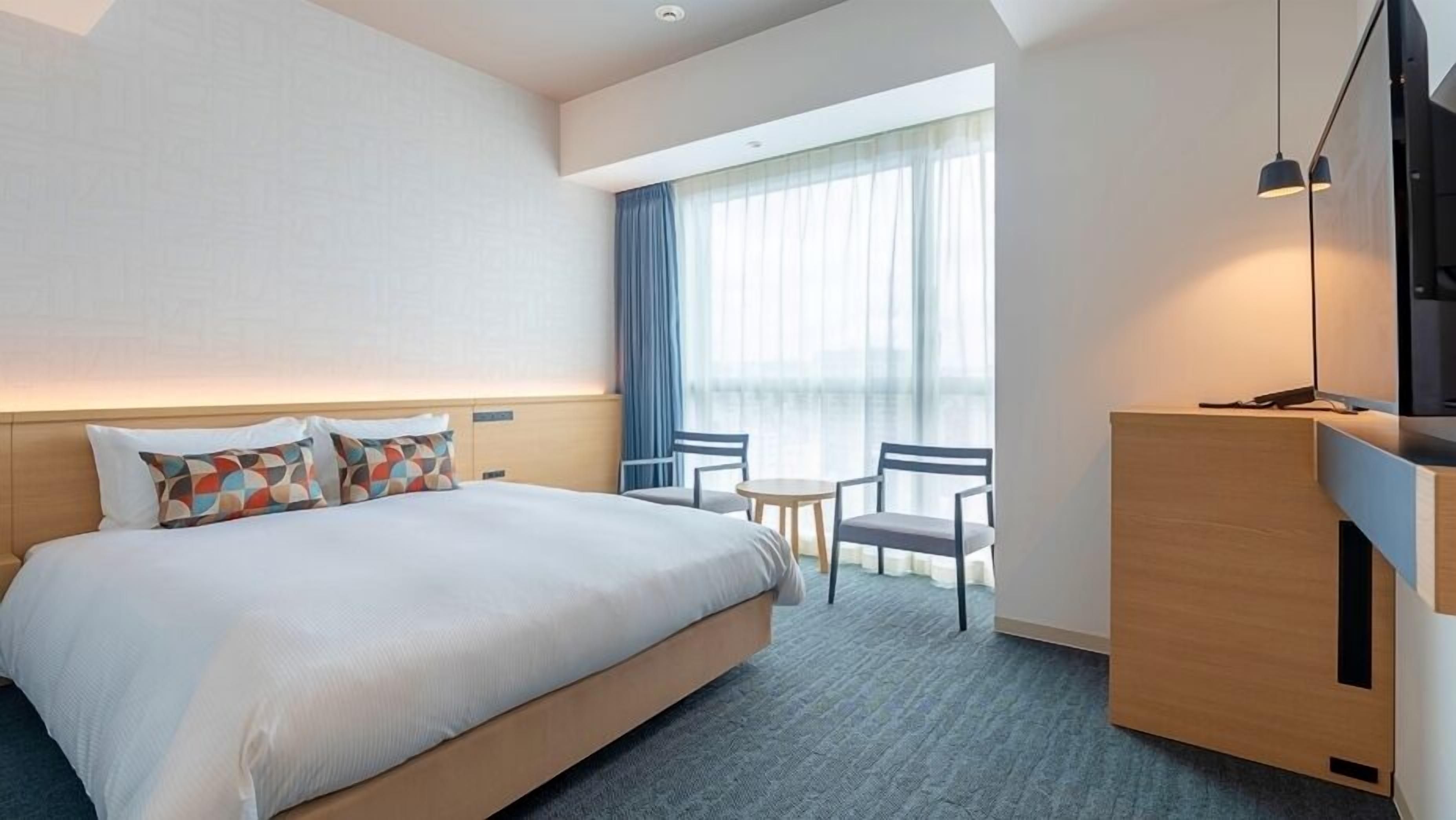 Een hotelkamer met een bed, bureau, stoel en televisie.
