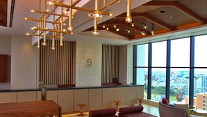 A modern hotel lobby with a reception desk, seating area, and large windows offering city views. - La'gent Hotel Okinawa Naha (Naha)