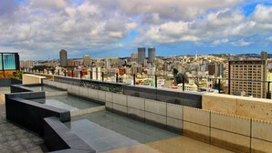 A rooftop terrace with a cityscape view, featuring a modern design with geometric seating and a tiled floor. - La'gent Hotel Okinawa Naha (Naha)