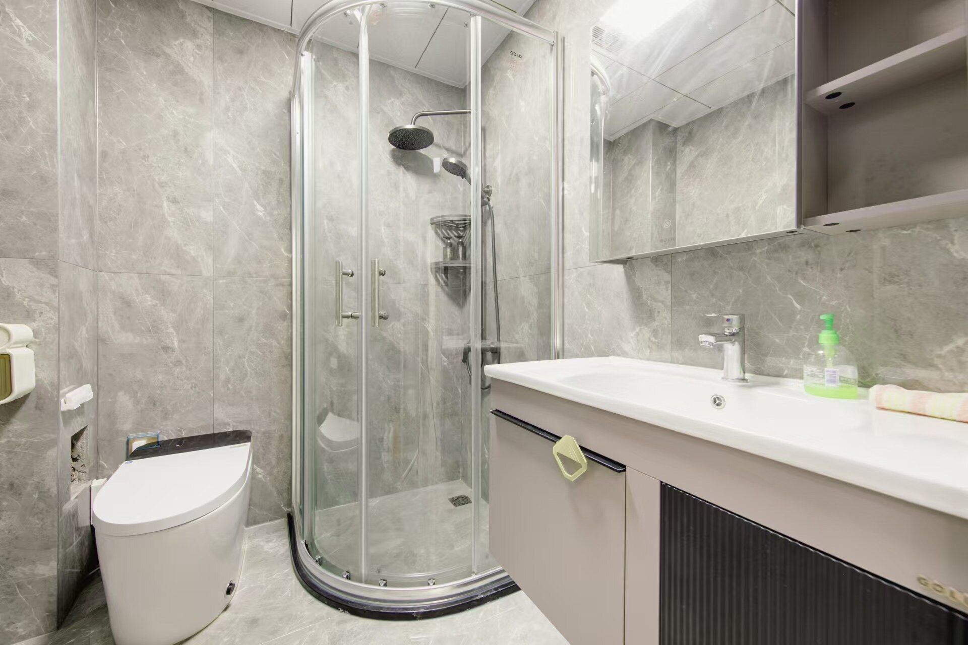 A modern bathroom with a glass-enclosed shower, a white toilet, and a vanity with a mirror and sink.