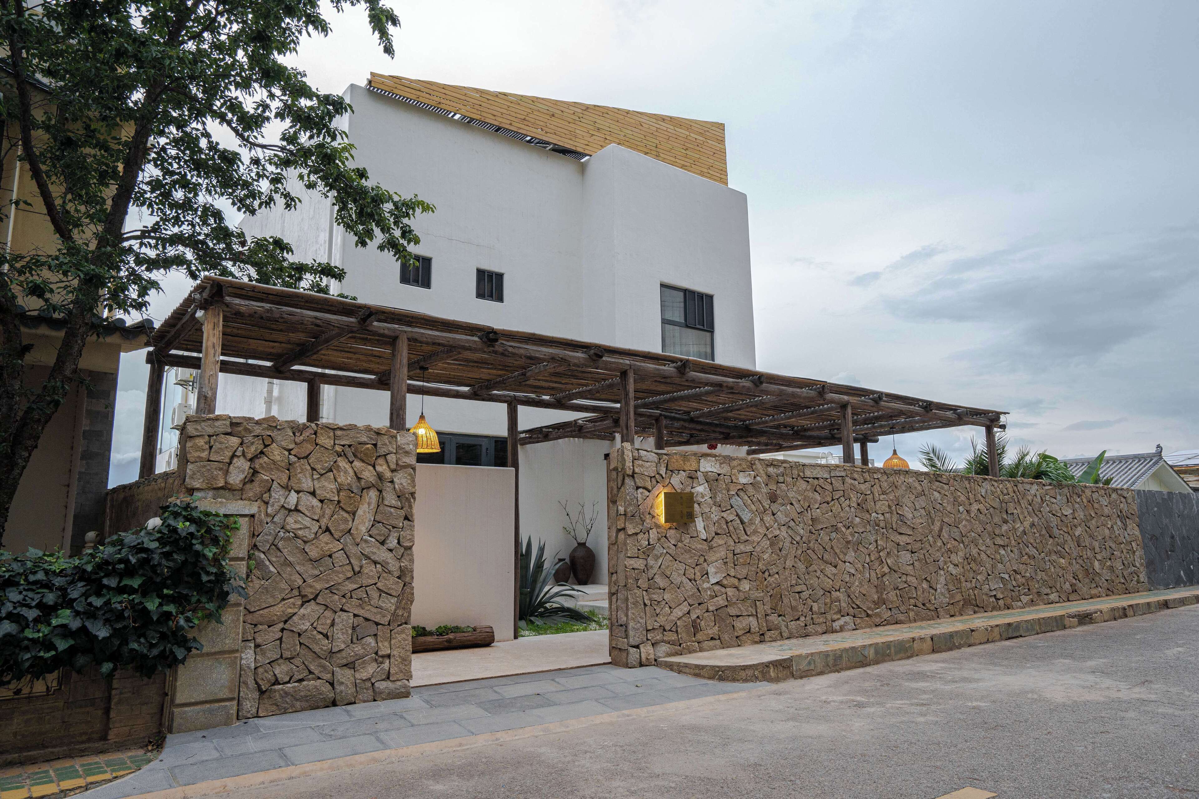 A modern building with a stone facade, a wooden pergola, and a clear sky.