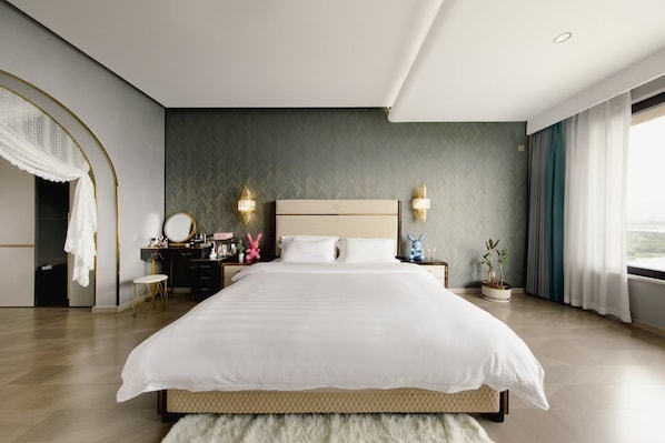 Una habitación de hotel moderna con una cama grande, un tocador con espejo y dos apliques de pared.