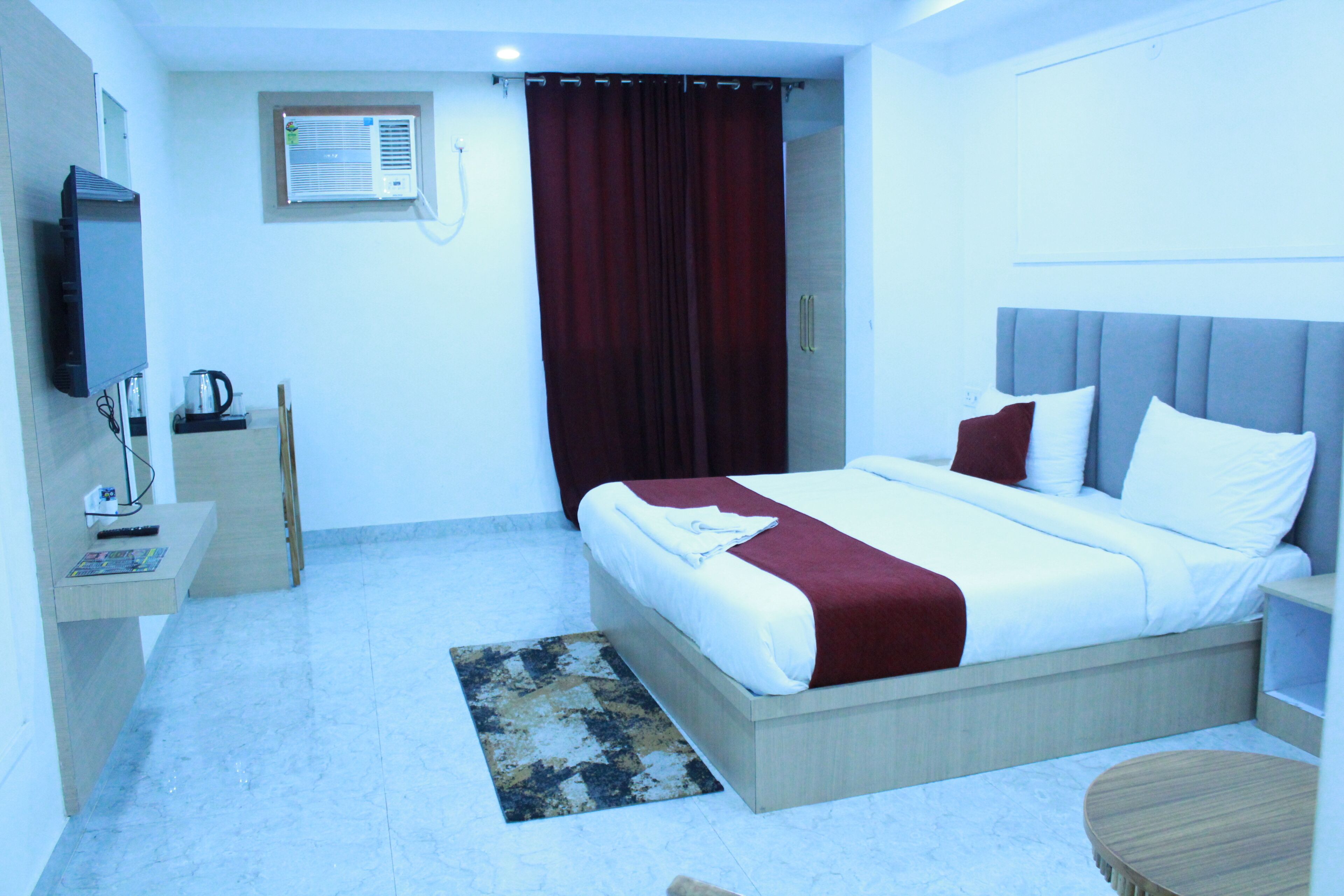 Habitación de hotel con cama, televisor, cafetera y una pequeña mesa.