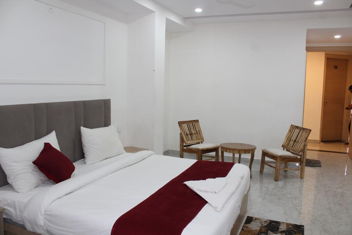 Una habitación de hotel con una cama, dos sillas, una mesita y una puerta.