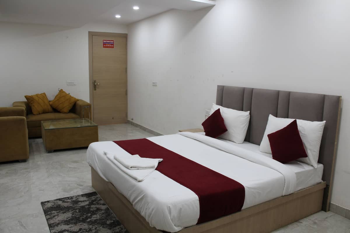 Una habitación de hotel con cama, sofá, una mesita de vidrio y una puerta.