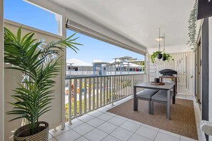 A balcony with a dining table, chairs, and potted plants.