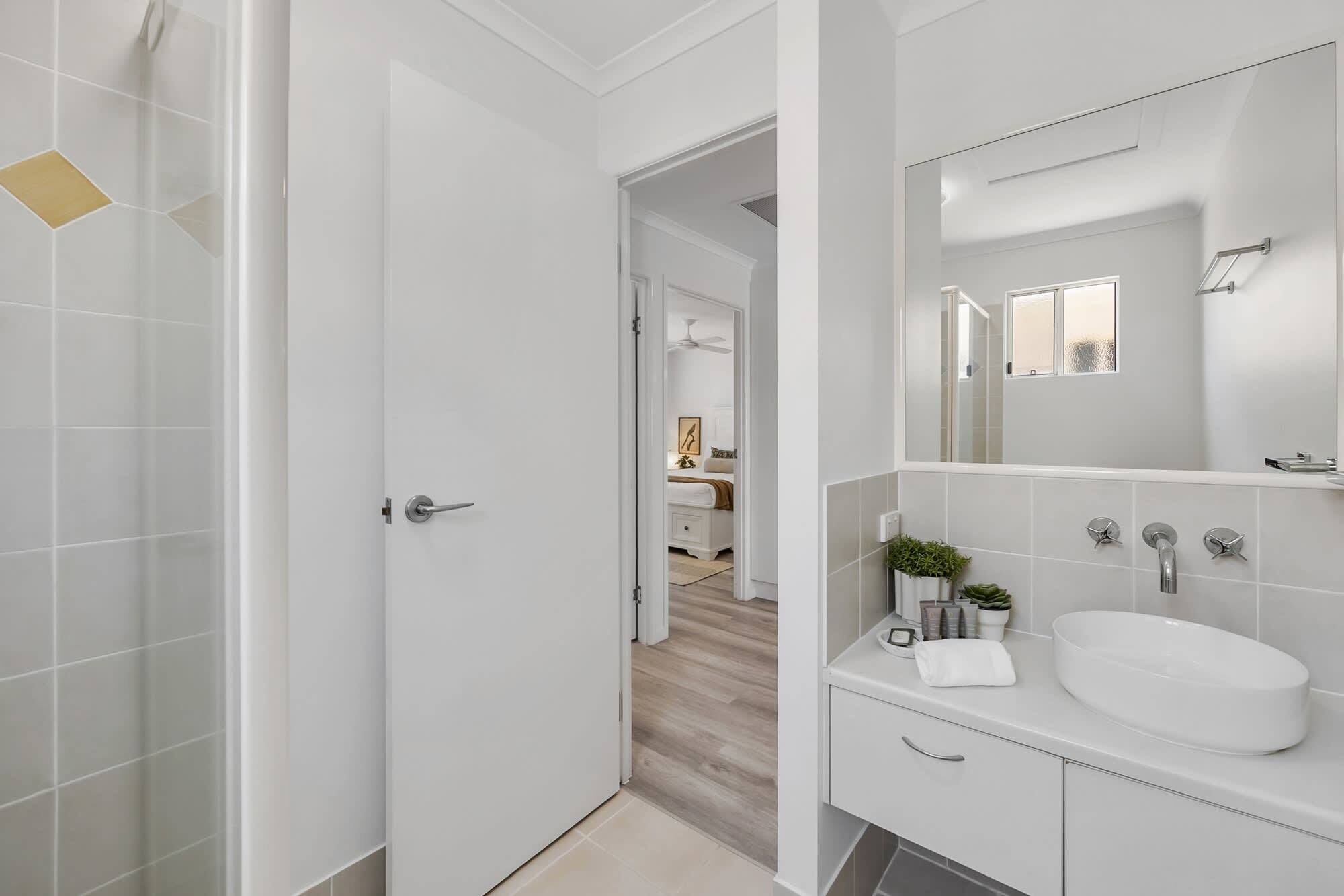 A modern bathroom with a white sink, mirror, and shower.