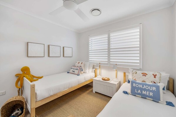 A room with a bed, a small table, a chair, and a window with blinds.