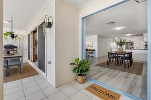 A modern interior with a dining area, kitchen, and a welcome mat.