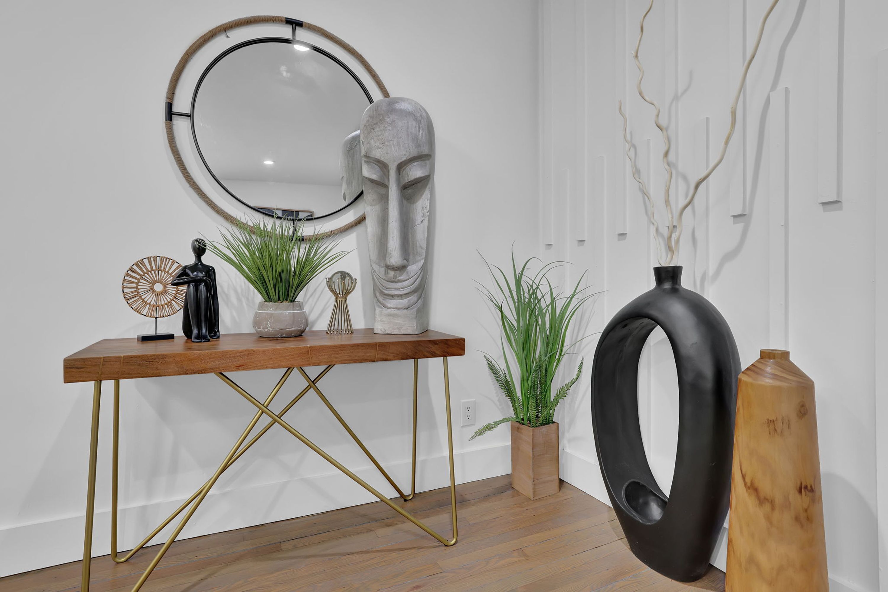 A wooden console table with a mirror, decorative items, and plants.