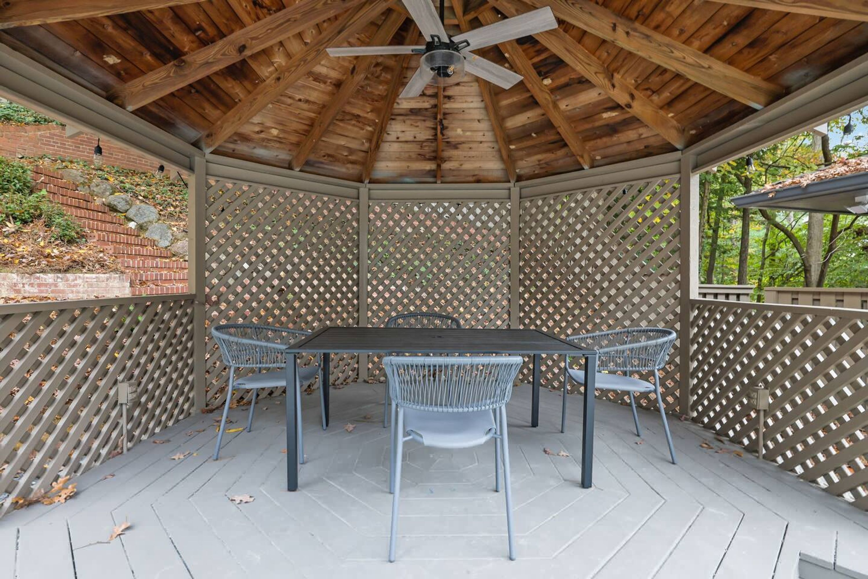 Un portico coperto con tavolo e sedie, travi in legno a vista e una recinzione a graticcio.