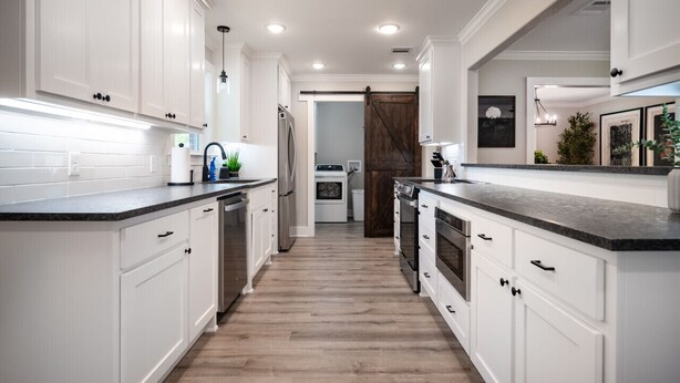 A modern kitchen with white cabinetry, a wooden floor, and a central island.
