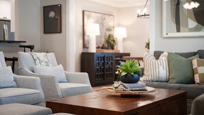 A modern living room with a wooden coffee table, grey sofas, and a potted plant.