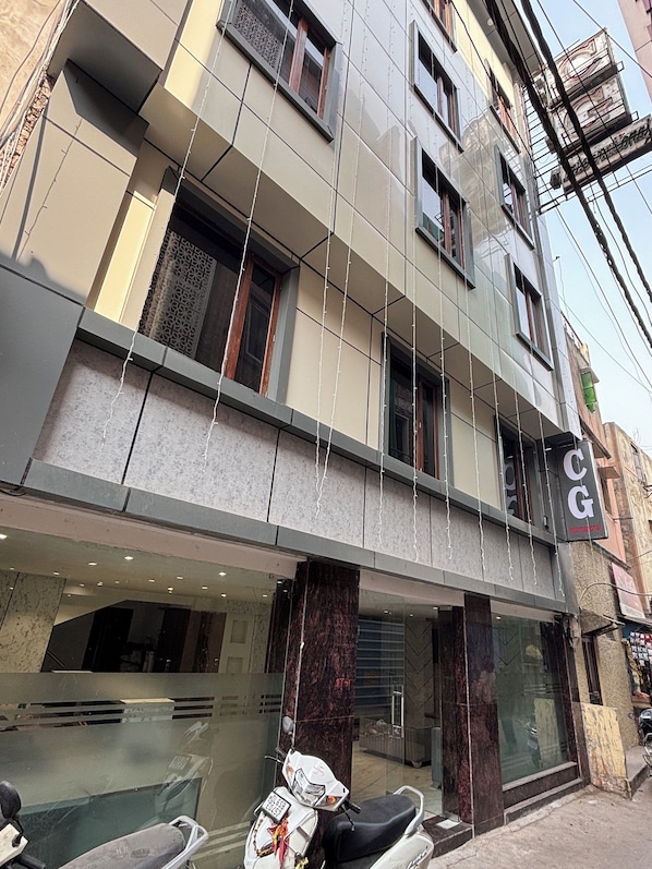 A multi-story building with a CG International sign, large windows, and a parked scooter outside. - Hotel CG International (New Delhi)