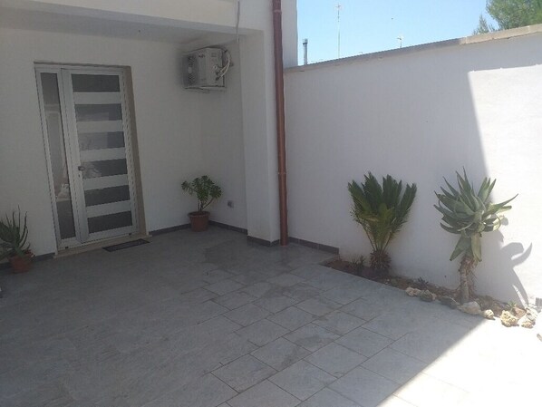 A small, enclosed outdoor area with a tiled floor, a door, and potted plants. - Da Vinci 86 - Apartment by the Sea. (Porto Cesareo)
