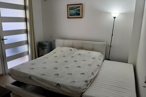 A bedroom with a bed, a bedside lamp, a radiator, and a window with curtains. - Da Vinci 86 - Apartment by the Sea. (Porto Cesareo)