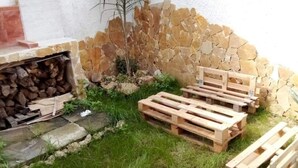 En stenmur, en träpall och en hög med ved.