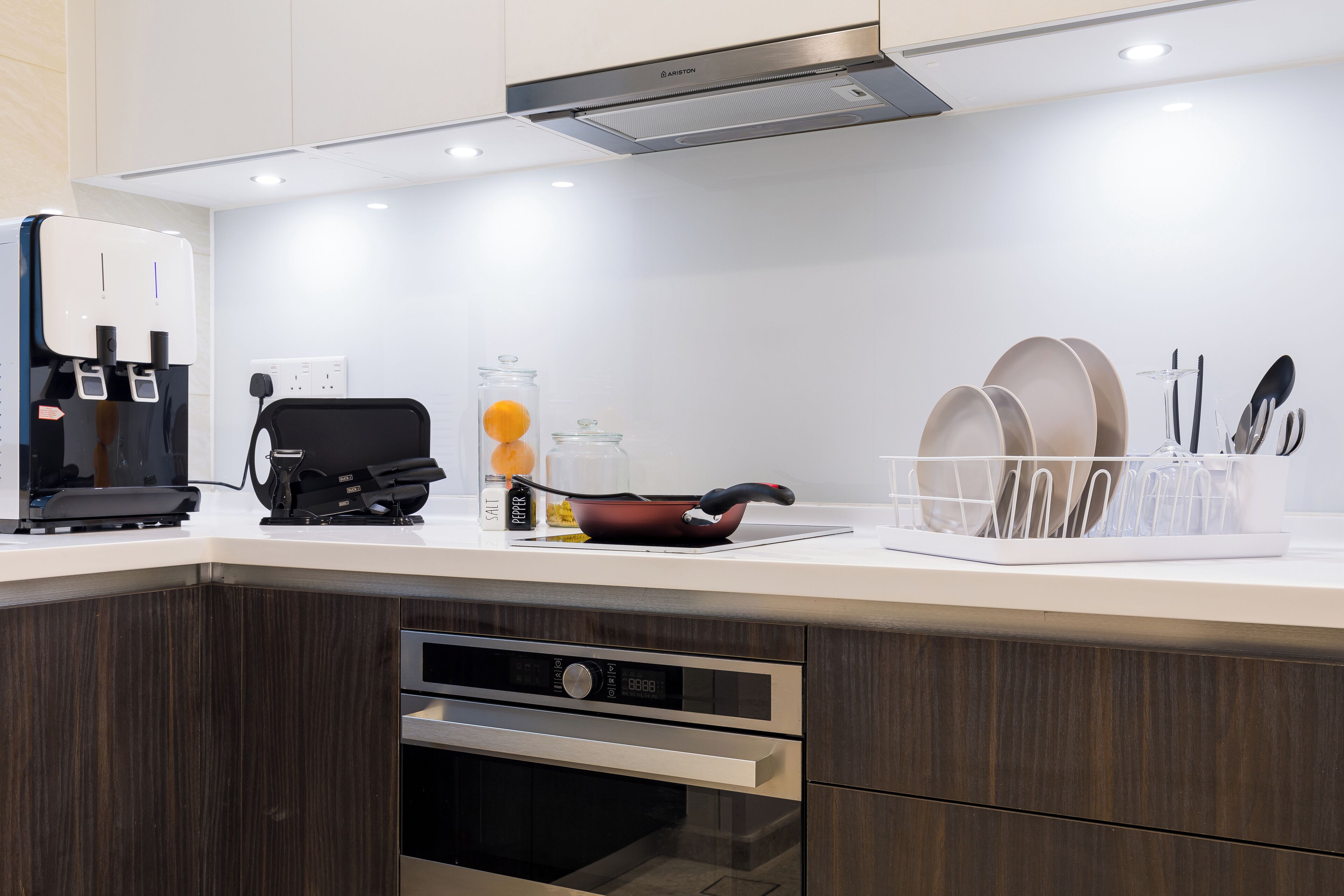 Una cocina moderna con cafetera integrada, tetera y sartén sobre la encimera.