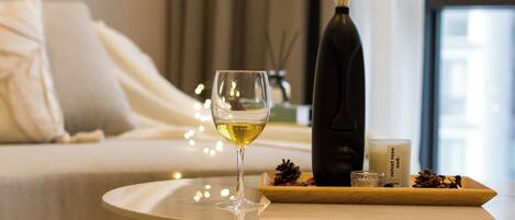Una mesa ordenada con una copa de vino blanco, una vela y un florero decorativo con flores secas.