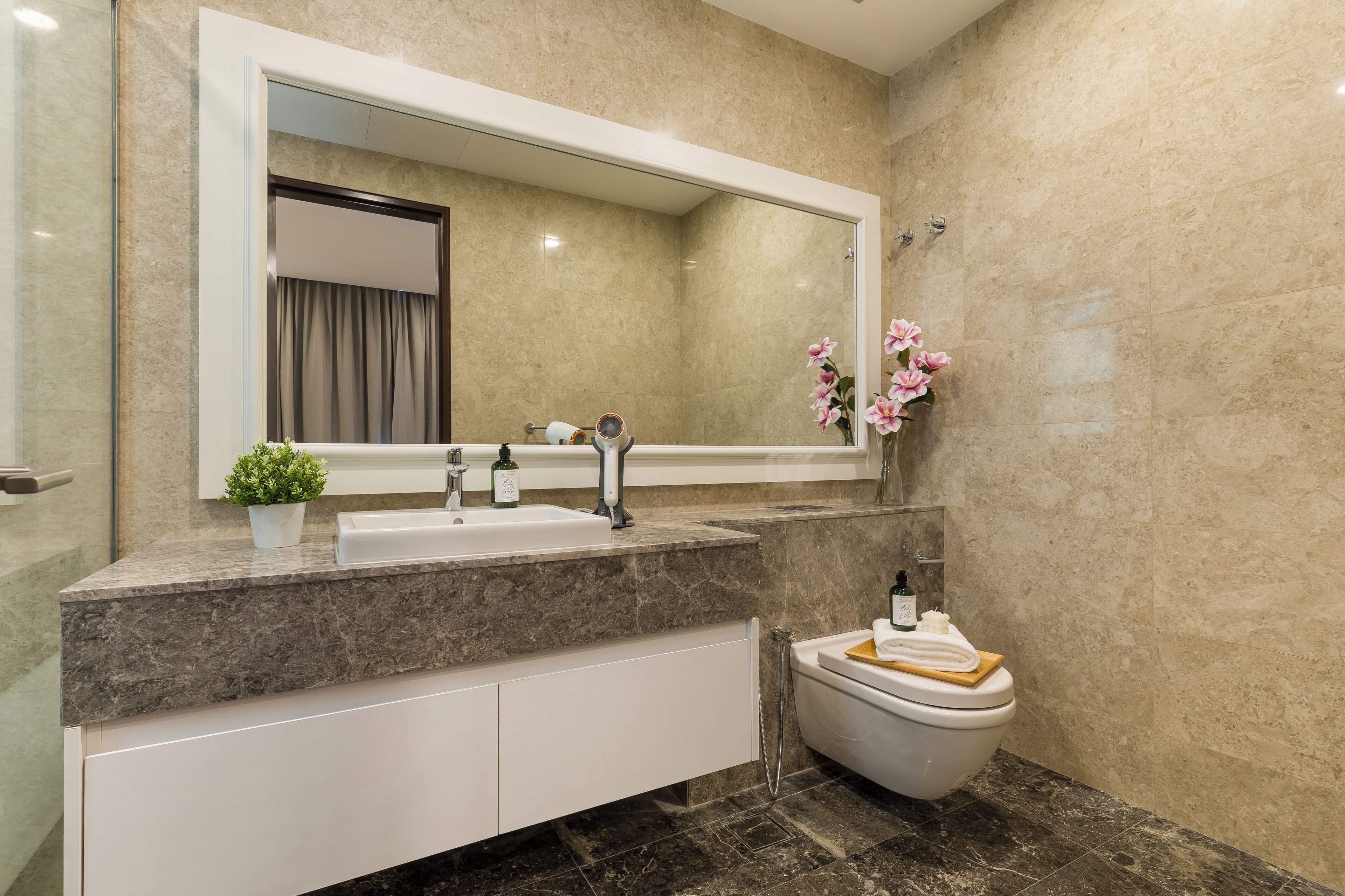 A modern bathroom with a large mirror, a sink, a toilet, and a shower area.