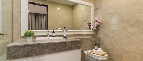 A modern bathroom with a large mirror, a sink, a toilet, and a shower area.